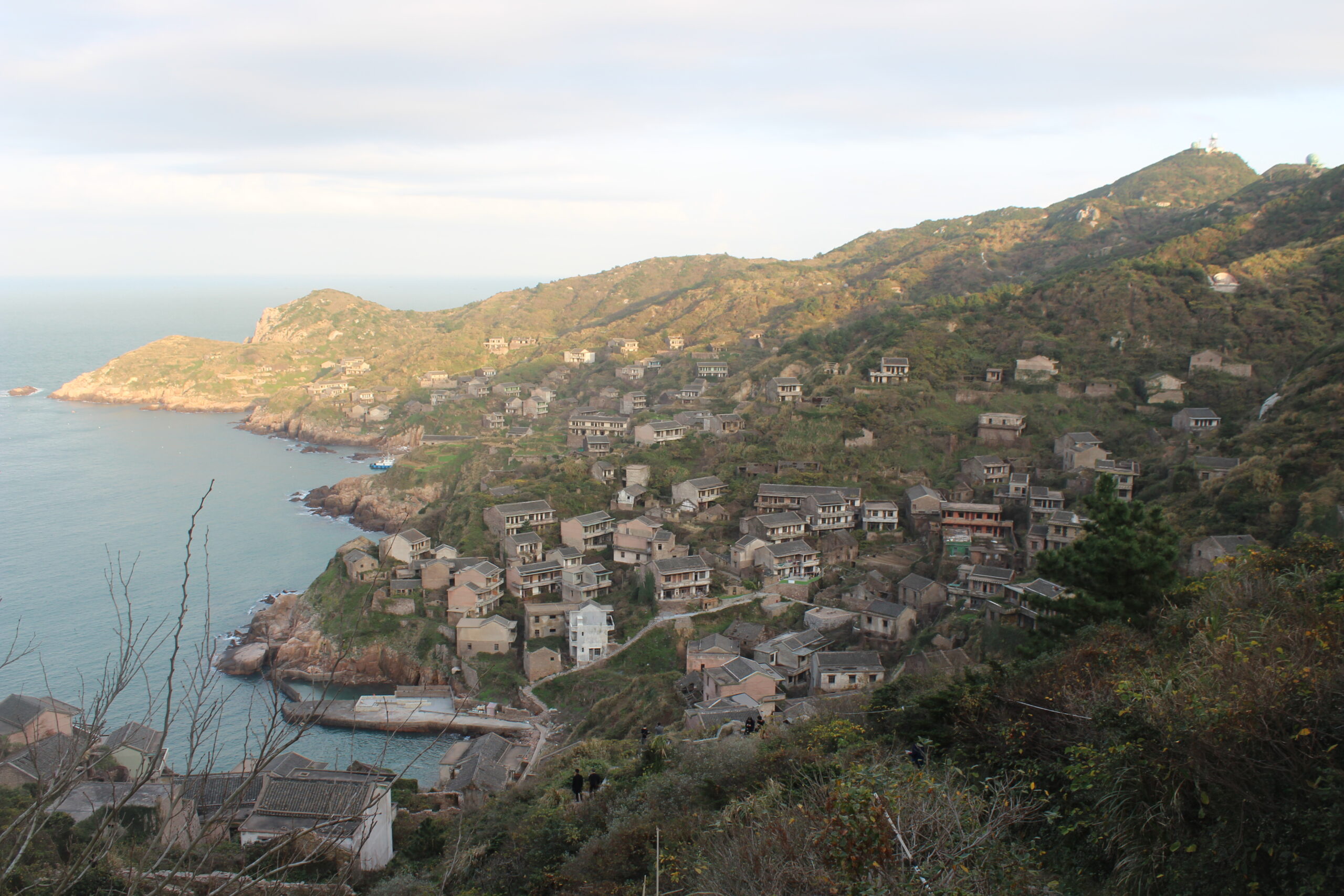 Abandoned coastal village reclaimed by vegetation and overlooking the sea